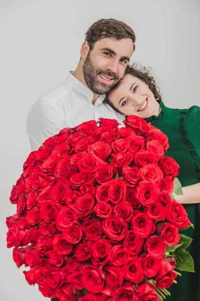 Begreppet sann kärlek. Kärleksfullt par står tillsammans, skiner av lycka, håller underbara gäng rosor. — Stockfoto