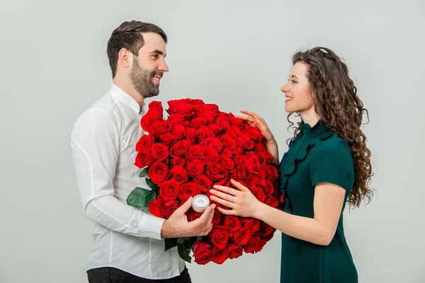 Красивий чоловік оголошує своє кохання кучерявій дівчині з кільцем і квітами. Вона скаже "так" . — стокове фото