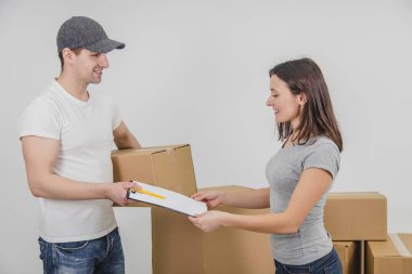 Genç bir kadın yeni bir yere taşınıyor. Teslimatçı bütün karton kutuları yeni dairesine taşıdı ve imzasını bekliyor..