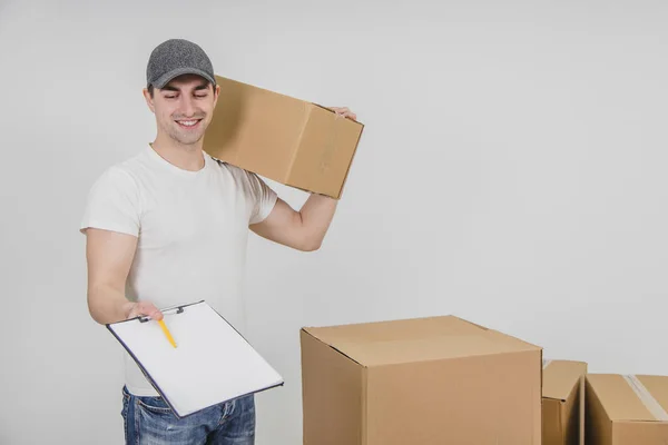 Молодий чоловік, що стоїть з картонною коробкою на плечі, посміхається, розширюючи буфер обміну для підпису . — стокове фото