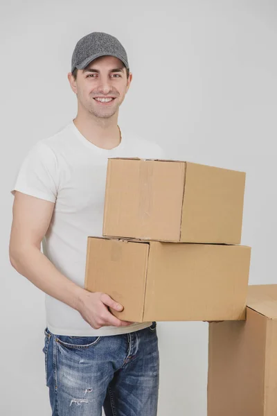 Leverancier staande, met twee kartonnen dozen, kijkend naar de camera, glimlachend. — Stockfoto