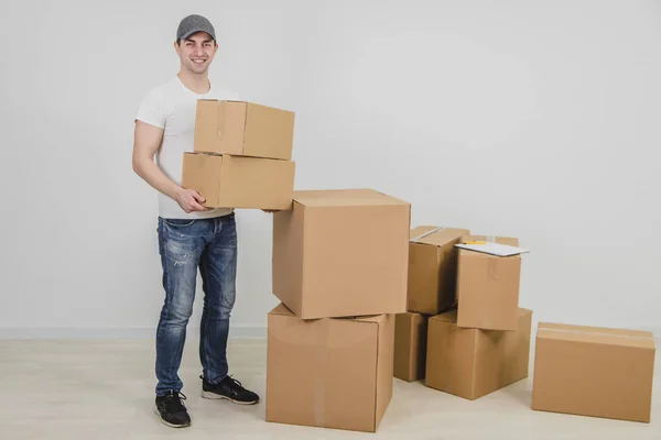 Entrega homem de pé, segurando duas caixas de papelão, olhando para a câmera, sorrindo . — Fotografia de Stock