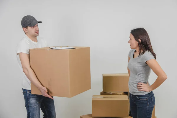 O entregador transportou todas as caixas de papelão para o novo apartamento feminino, mas tarde demais e a mulher está irritada por causa disso. Courier está olhando para ela com expressão facial inocente . — Fotografia de Stock