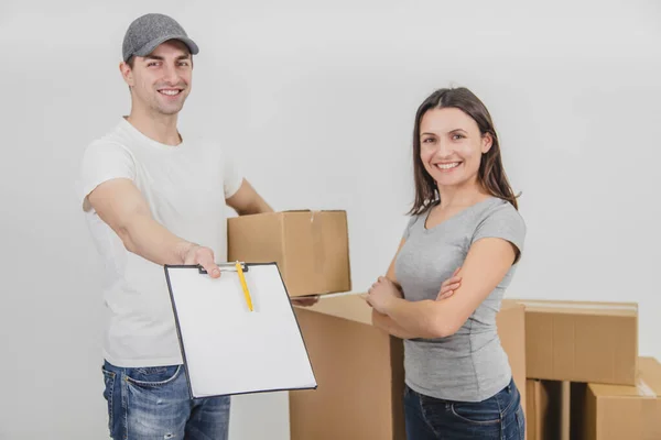 Happy delivery man transported boxes into new apartment of lovely young woman and is showing signed declaration, smiling. Both are happy for cooperation. — Stock Photo, Image
