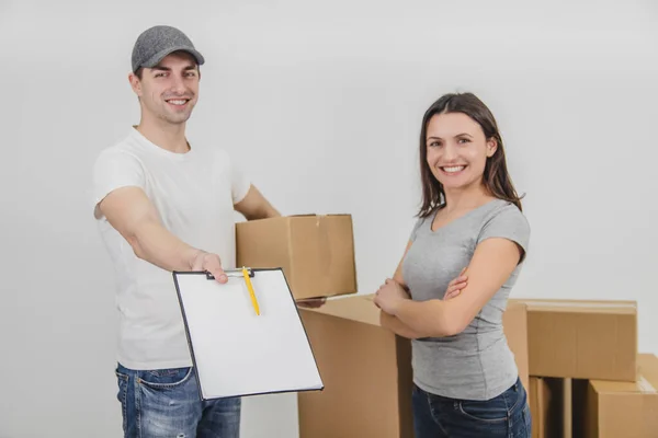 Happy delivery man transported boxes into new apartment of lovely young woman and is showing signed declaration, smiling. Both are happy for cooperation. — Stock Photo, Image