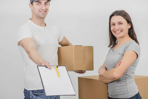 Cortado borrado homem de entrega feliz transportado caixas em novo apartamento de linda jovem e está mostrando declaração assinada, sorrindo. Ambos estão felizes pela cooperação . — Fotografia de Stock