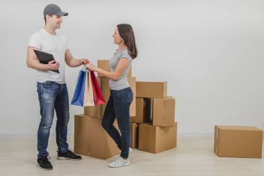 Yakışıklı kurye, yeni daireye taşınması durumunda genç bir bayana renkli çantalar içinde hediyeler dağıttı. Kadın gerçekten mutlu, gülümsüyor..