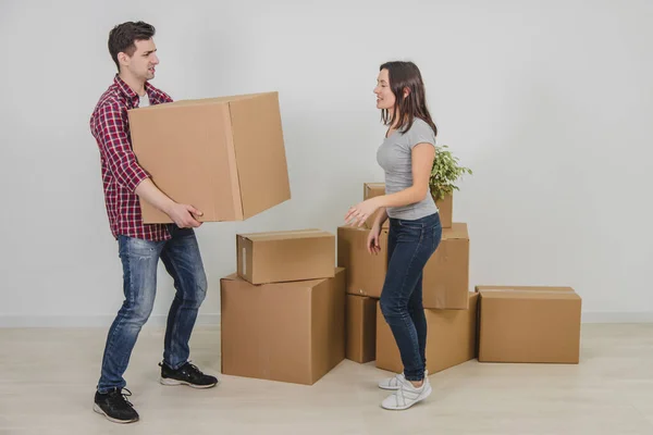 Um casal num apartamento novo. O jovem está exausto. Ele não pode segurar caixa pesada mais, mas a mulher não sabe onde colocá-lo . — Fotografia de Stock