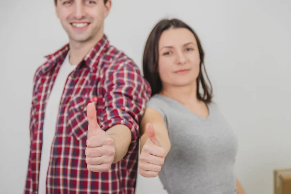 Cortado borrado feliz homem e mulher de pé em seu novo apartamento, dando polegares para cima, sorrindo . — Fotografia de Stock