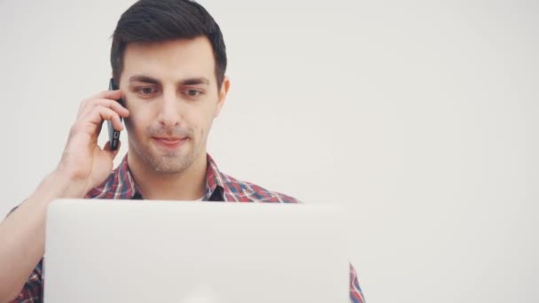 Concentrated young man standing, using laptop, looking for appropriate apartments to move, then calling. — Stock Video