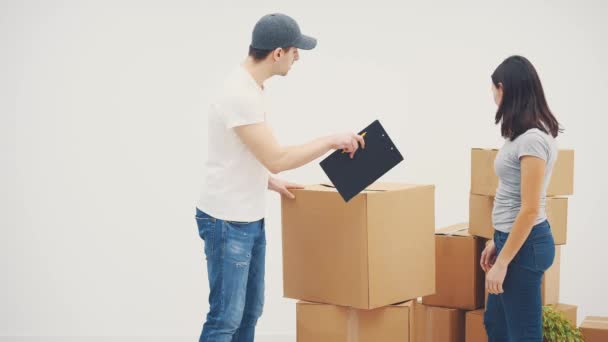 Jonge vrouw verhuist naar een nieuwe plek. Ze belde een bezorger om alle kartonnen dozen naar een nieuwe flat te brengen. Ze onderhandelen.. — Stockvideo