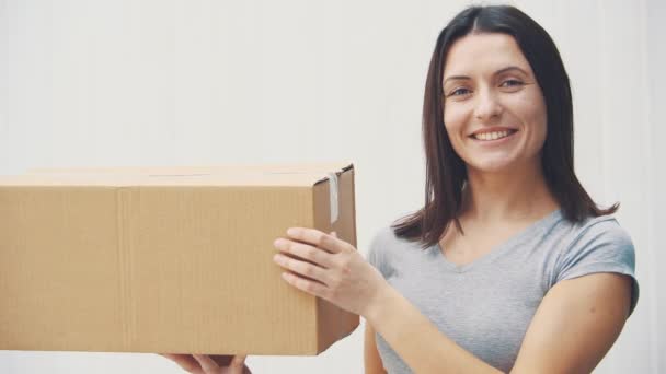 Pretty young woman is holding big carton box, giving thumb up, smiling. — Stock Video