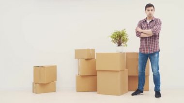 Çiçek saksısı ve karton kutular taşıyan yakışıklı genç adam taşınıyor..