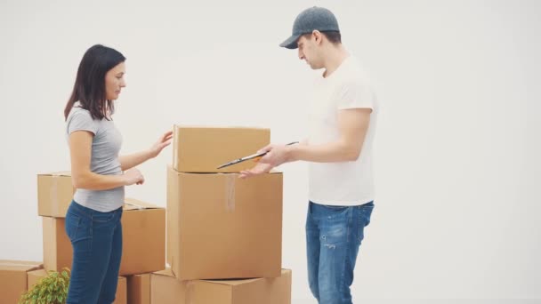 Una joven mudándose a un lugar nuevo. Ella está de pie hablando con el repartidor sobre el transporte de cajas grandes . — Vídeo de stock