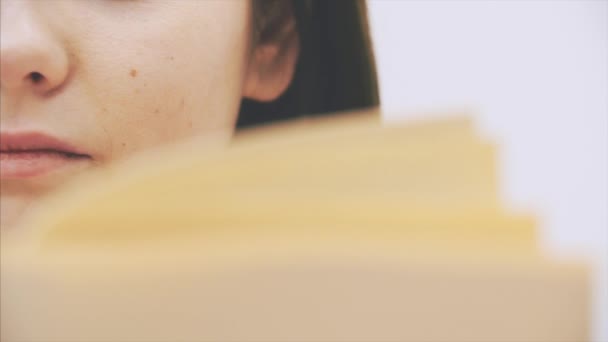 Rostro semilateral recortado de una joven inquisitiva leyendo un libro, completamente involucrada y emocionada . — Vídeo de stock