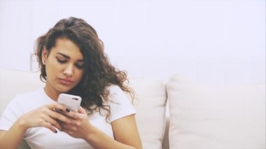 Sevimli Afro-Amerikalı kız koltukta oturuyor, elinde telefonla, mesajlaşıyor, iç çekiyor, yorgun görünüyor..