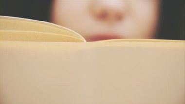 Meraklı genç bir kadın kitap okuyor, tamamen ilgili ve heyecanlı görünüyor..