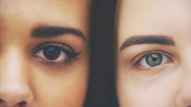 Cropped half-side faces of young beautiful afro-american and caucasian girls, looking at the camera, then closing their eyes. — Stock Video