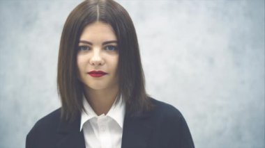 Siyah takım elbiseli genç ve çekici bir iş kadını havada öpüşüyor, poz veriyor, mutlu bir şekilde gülümsüyor..