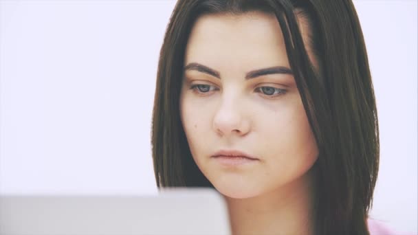 Menina morena branca bonito com laptop, surfando na internet, estreitando os olhos . — Vídeo de Stock