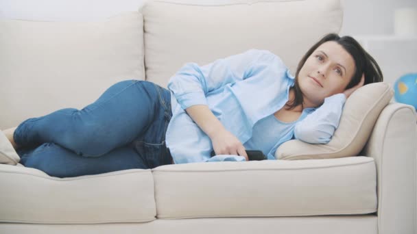 Satisfait les femmes brunes regarde la télévision et s'endort sur le canapé à la maison. La femme rêve de rêves agréables. 4K . — Video