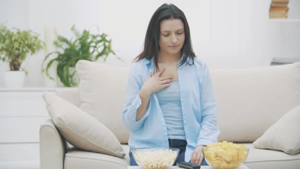 Mujer feliz está tratando de elegir entre el maíz pop y patatas fritas. La mujer guapa está masticando maíz. 4K . — Vídeos de Stock