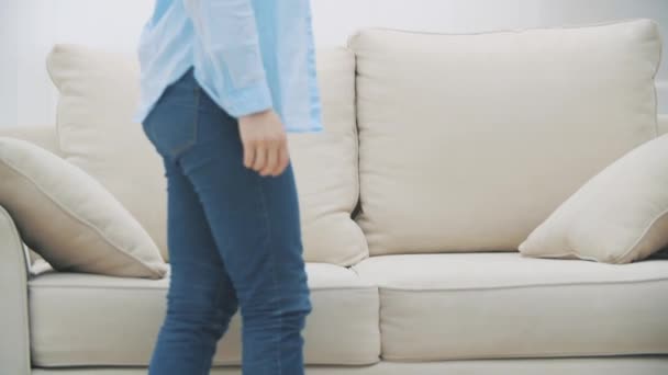 Långsamt. Den unga kvinnan ramlar på soffan bakom sig. Hon känner sig yr. Närbild. 4k. — Stockvideo