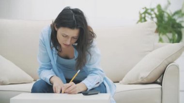 İş kadını akıllı telefonuyla konuşuyor ve evdeki kanepede oturuyor. Ağır çekim. Uzayı kopyala 4k.