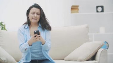 Çekici esmer kadın telefon oyununa bulaşmış. El sallıyor, seviyeyi geçmeye çalışıyor. Ağır çekim. Uzayı kopyala 4k.