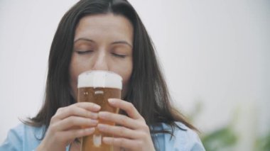 Yavaş ol. Tatmin olmuş kadın biranın kıvılcımına bakıyor ve tadına bakıyor, evdeki kanepede oturuyor. Uzayı kopyala Kapatın. 4k.