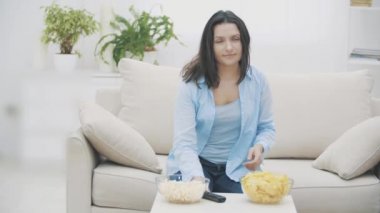 Yavaş ol. Mutlu kadın televizyonu bir şok tabancasıyla açıyor ve büyük bir tabak dolusu patlamış mısır alıyor. 4k.