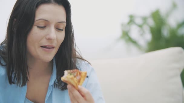 Lentamente. Primo piano di donna adorabile, che sorride ampiamente e mastica un pezzo di pizza. Deliziosa-buonissima. 4K . — Video Stock