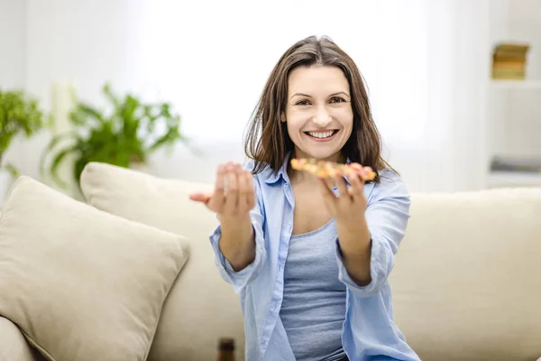 Smiling woman offers to taste delicious slice of pizza. Blurred forefront. Close up. Copy space.