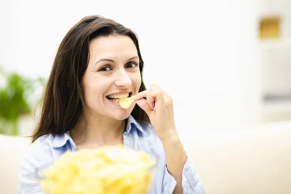 Feliz adorable morena ofrece un plato grande y profundo con papas fritas snack. Está saboreando bocadillos. De cerca. . —  Fotos de Stock