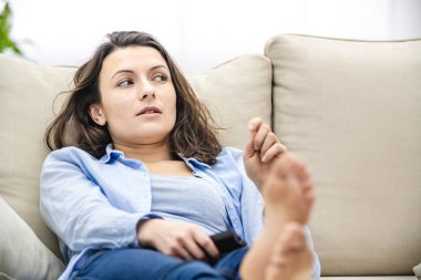 Ekin. Sıkılmış ve gevşemiş kadın televizyon seyrediyor, kanepede yatıyor. Kapat..