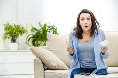 Şaşırmış bir kadın elinde kağıt çıkartma ve kalemle ağzını açıyor. Boşluğu kopyala.