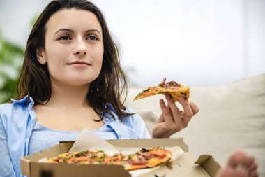 Kafkaslı kadın evde izole edilmiş lezzetli pizzalar yiyor. Kapatın. Boşluğu kopyala.