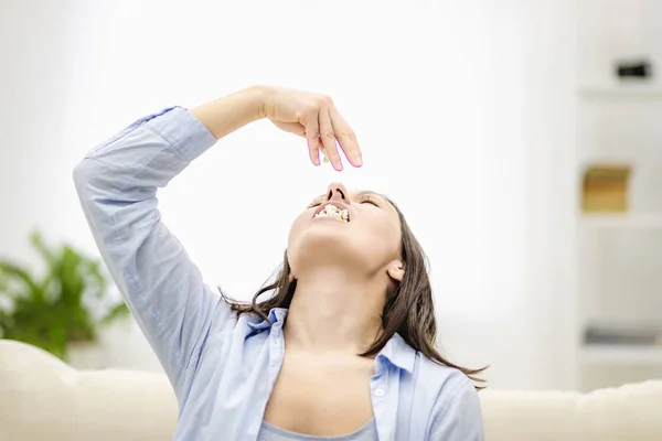 Eine wütende junge Frau schüttet Popcorn in den Mund. Nahaufnahme. — Stockfoto