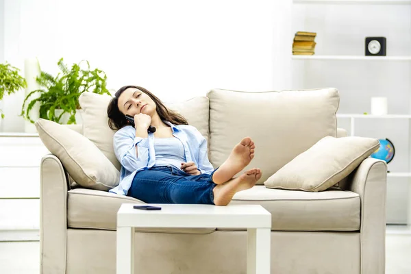 Eine gelangweilte junge Frau sitzt auf einem Sofa vor dem Fernseher. Kopierraum. — Stockfoto