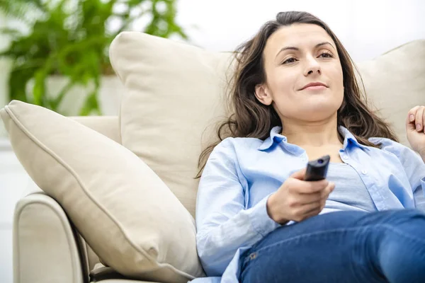Ernte. Gelangweilte und entspannte Frau sieht fern, auf einem Sofa liegend. Nahaufnahme. — Stockfoto