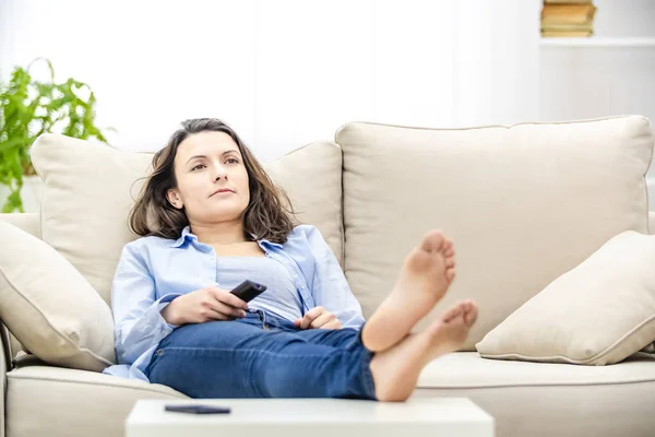 Nudná a uvolněná žena se dívá na televizi, jak leží na pohovce. Kopírovat prostor. — Stock fotografie