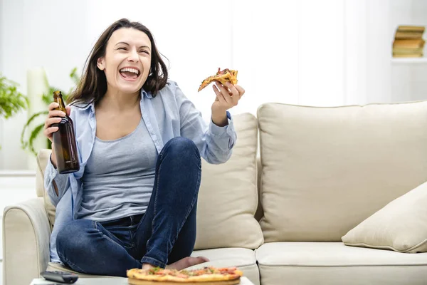Atrakcyjna kobieta pije zimne piwo i je pizzę, oglądając mecz w telewizji. — Zdjęcie stockowe