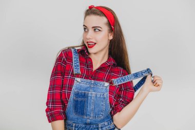 Ayakta duran tatlı kız, askısını kaldırıyor, yandan sevimli görünüyor..