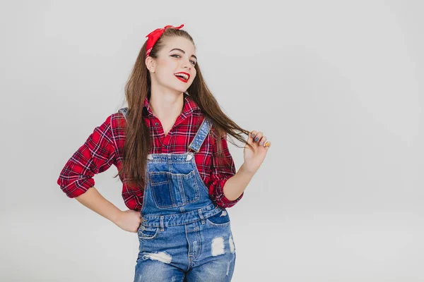 Hermosa joven de pie, sus manos akimbo, mirando a la cámara, sonriendo seducidamente, tocándose el pelo . —  Fotos de Stock