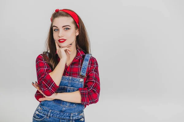 Hermosa joven en rojo de pie, cogida de la mano cerca de su barbilla, posando, mirando a la cámara seduciosamente . —  Fotos de Stock