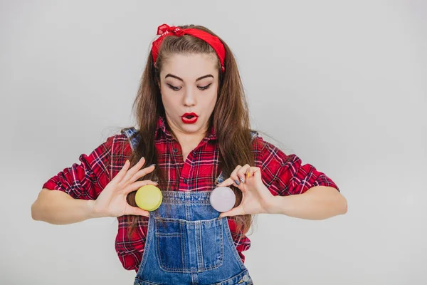 Jeune fille stupide ludique tient deux macarons à la place des boutons de son jean. Regard expressif . — Photo