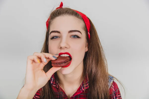 Schönes nettes junges Mädchen, das verführerisch leckere Schokoladenmakronen probiert. verrückt zufriedener Gesichtsausdruck. — Stockfoto