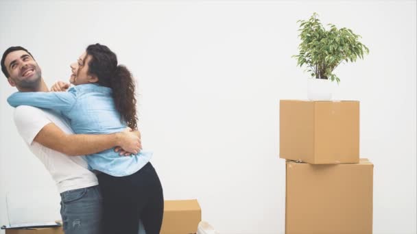 Una joven pareja se mudó a un nuevo apartamento juntos. Se están abrazando y acurrucándose. Pareja sonriente. 4K . — Vídeo de stock