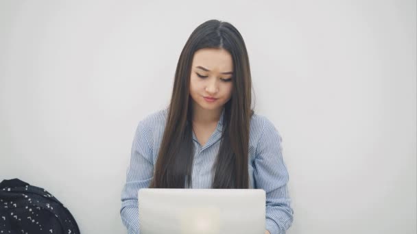 Belle mais fatiguée fille asiatique aux cheveux longs assis avec ordinateur portable sur ses genoux, massant les tempes, ayant quelques difficultés . — Video
