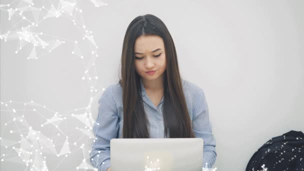 Bella ma stanca ragazza asiatica con i capelli lunghi seduta con il computer portatile sulle ginocchia, massaggiando templi, avendo alcune difficoltà . — Video Stock